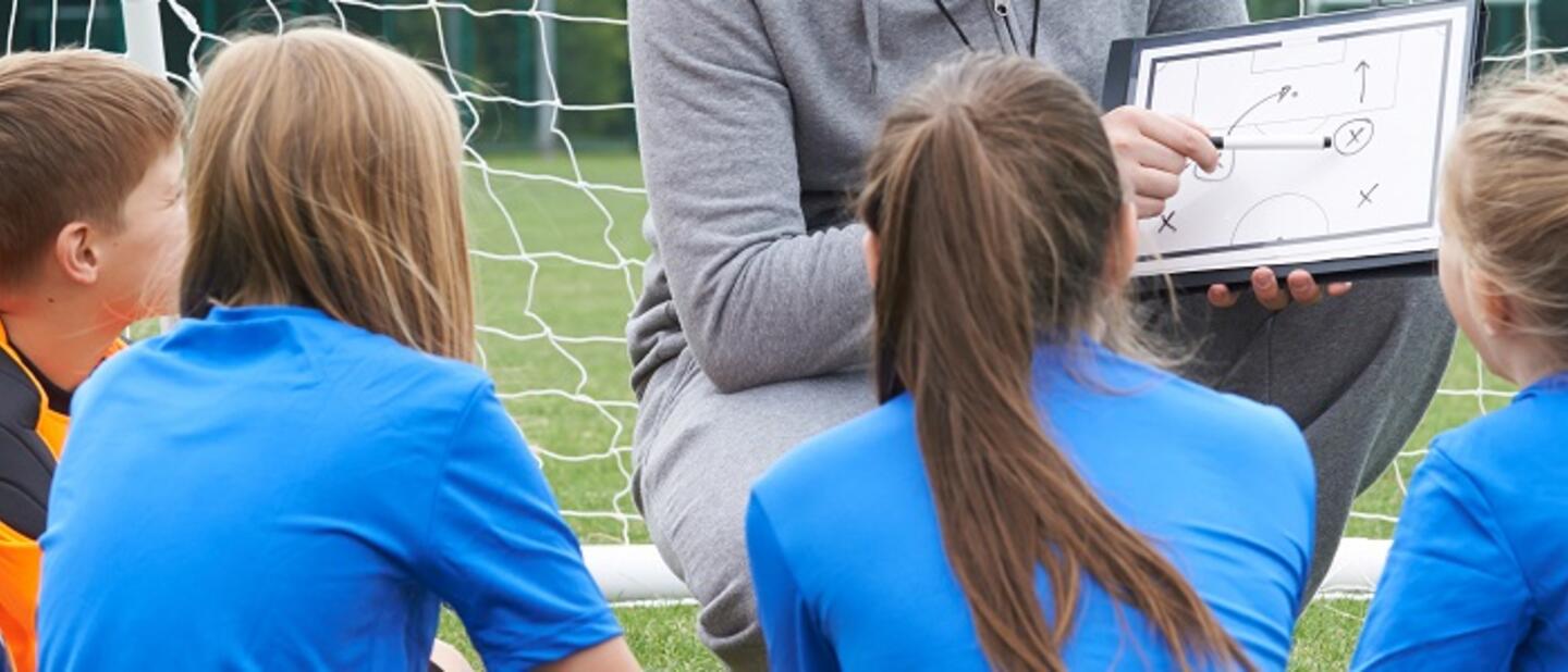 Kinderen voetbalteam luisteren naar coach