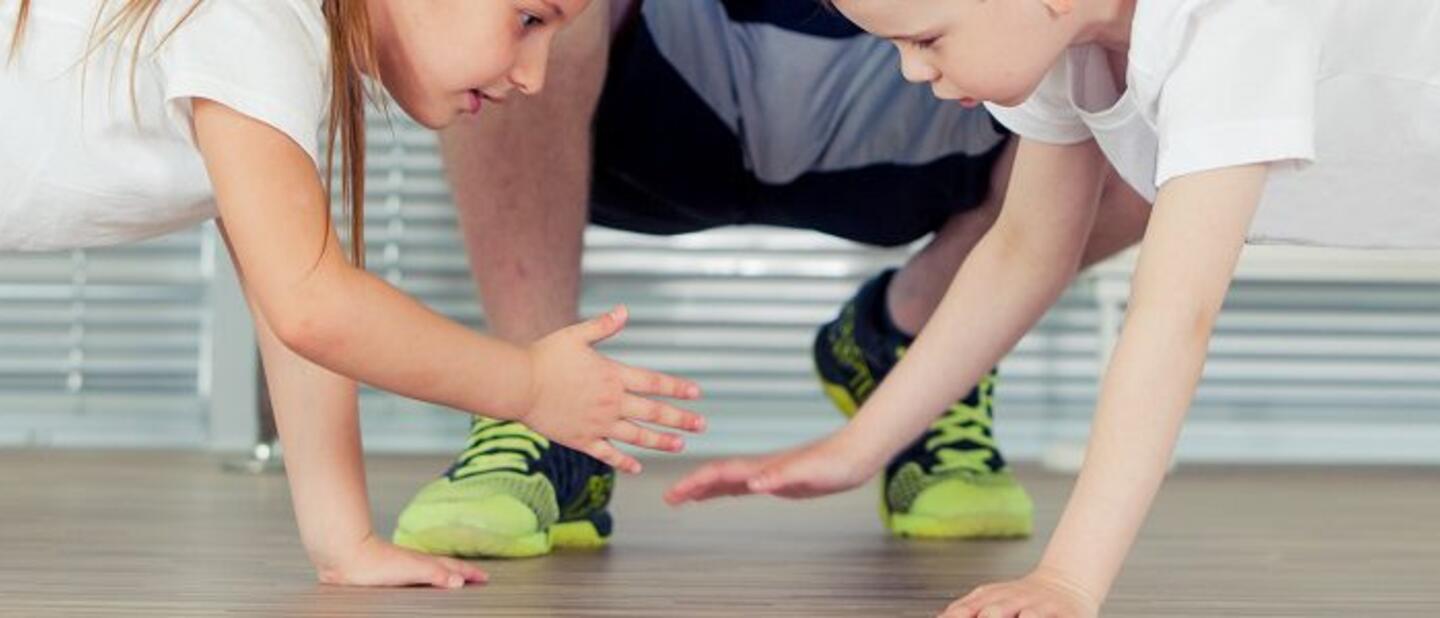 Twee kinderen in plankpositie die elkaars hand klappen