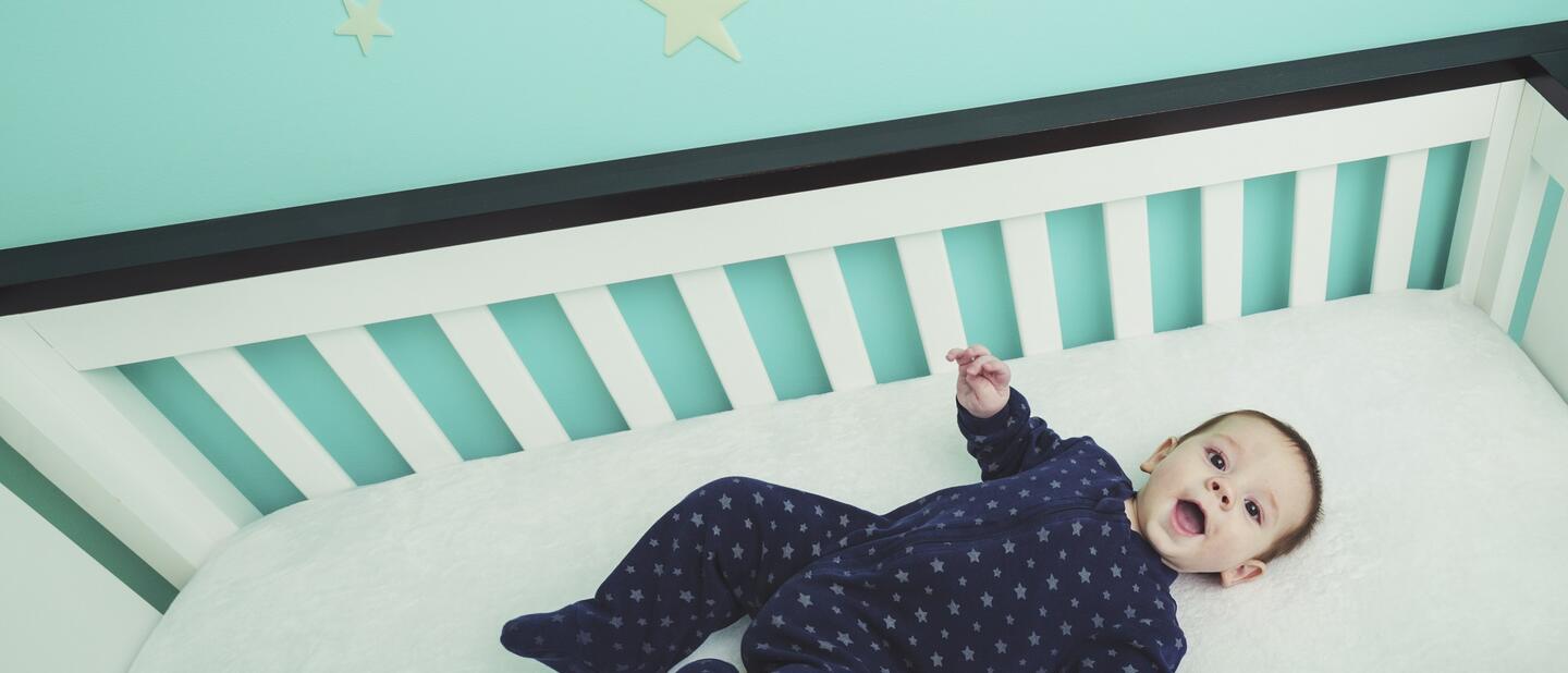 Baby liggend op rug in wieg