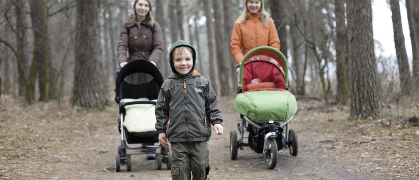 Kind in het bos samen met twee vrouwen met wandelwagens