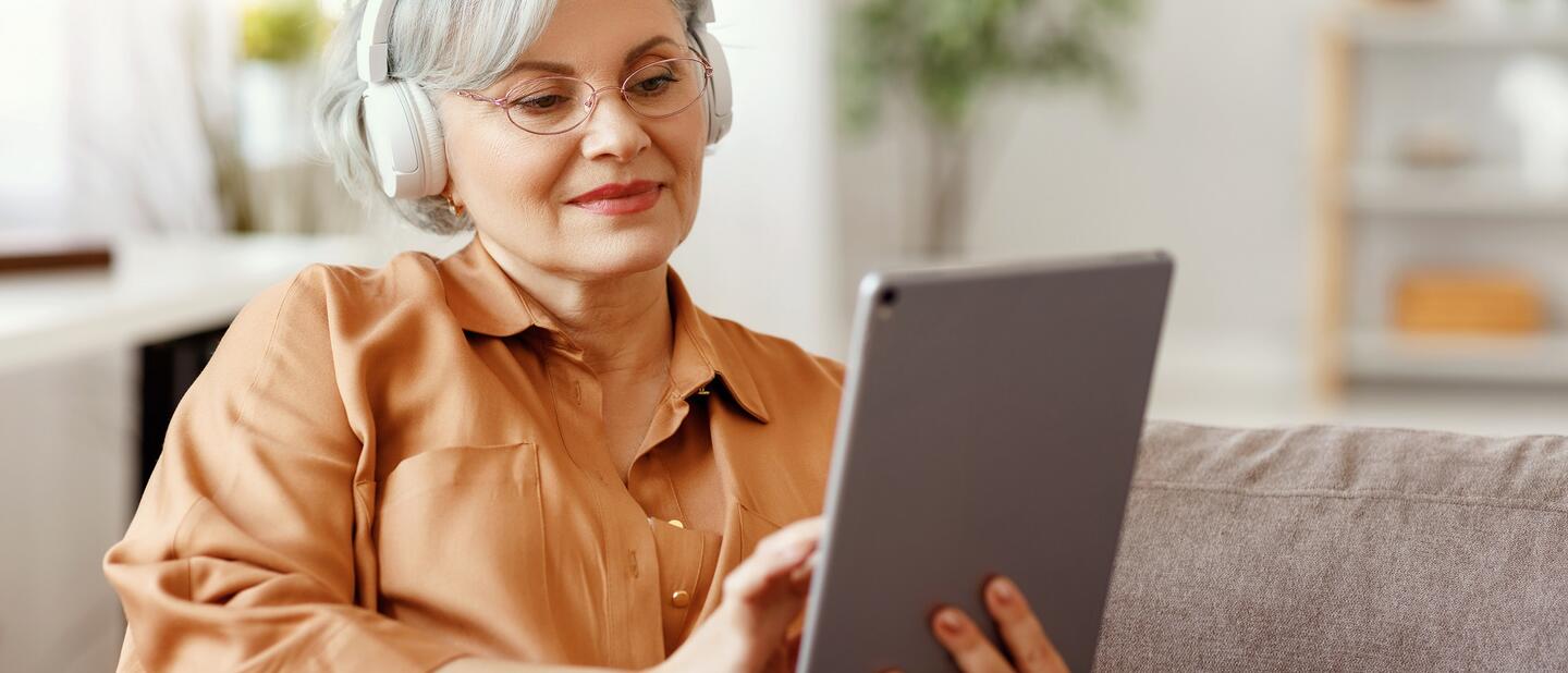 Oudere vrouw met koptelefoon op iPad