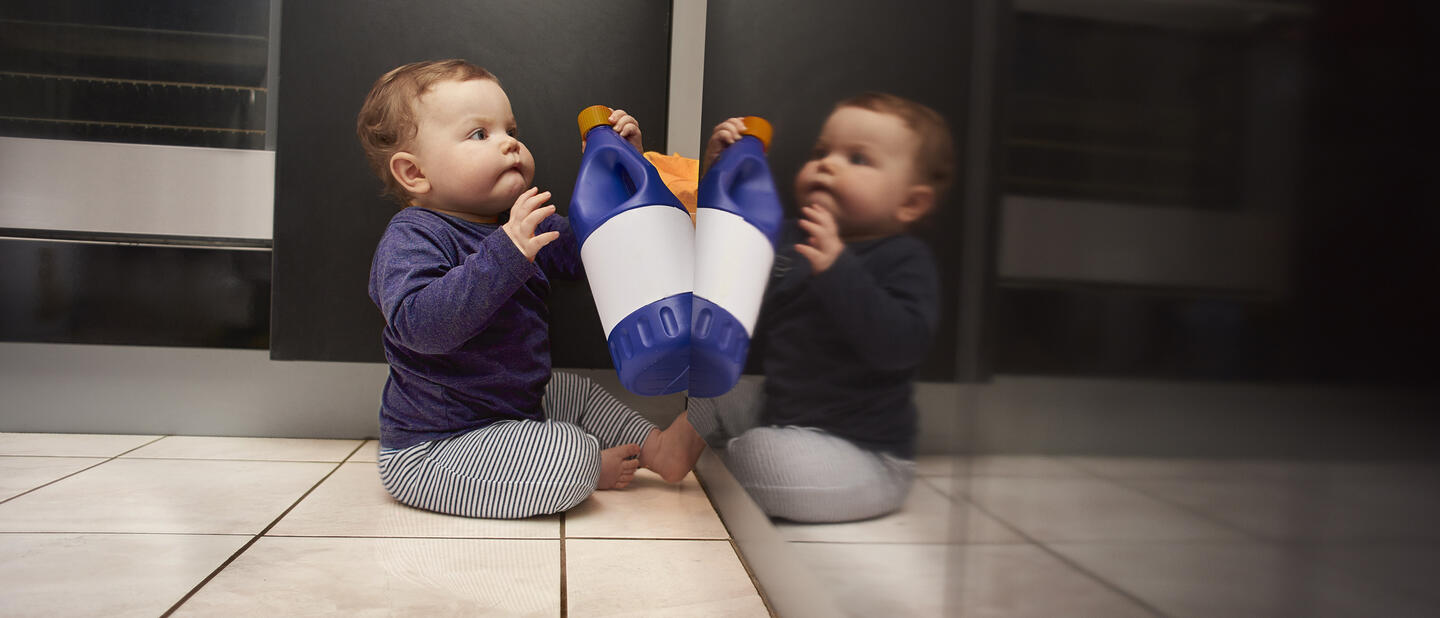 Baby speelt met fles schoonmaakmiddel