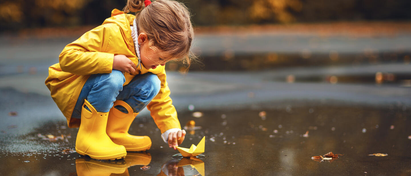 Kind bij water in regenkleding