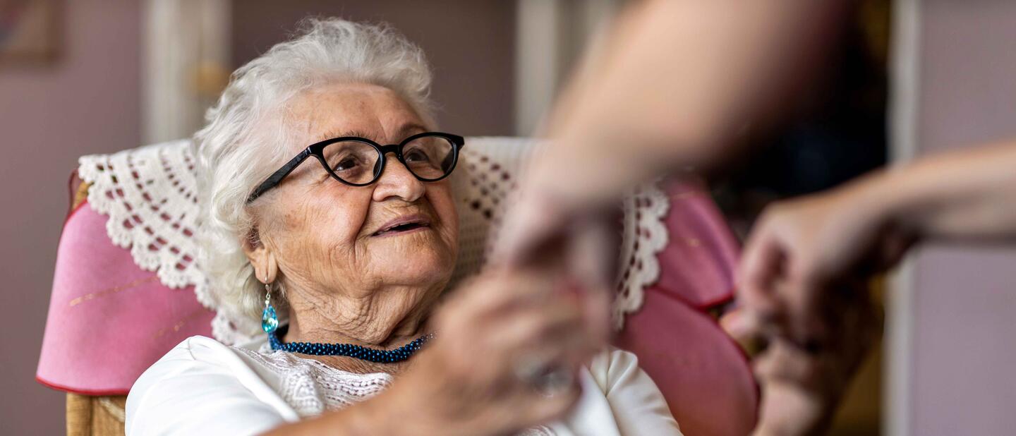 oudere dame wordt uit stoel geholpen