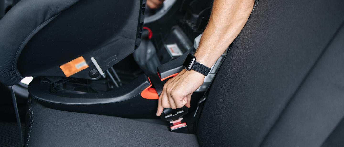 man zet autostoel vast